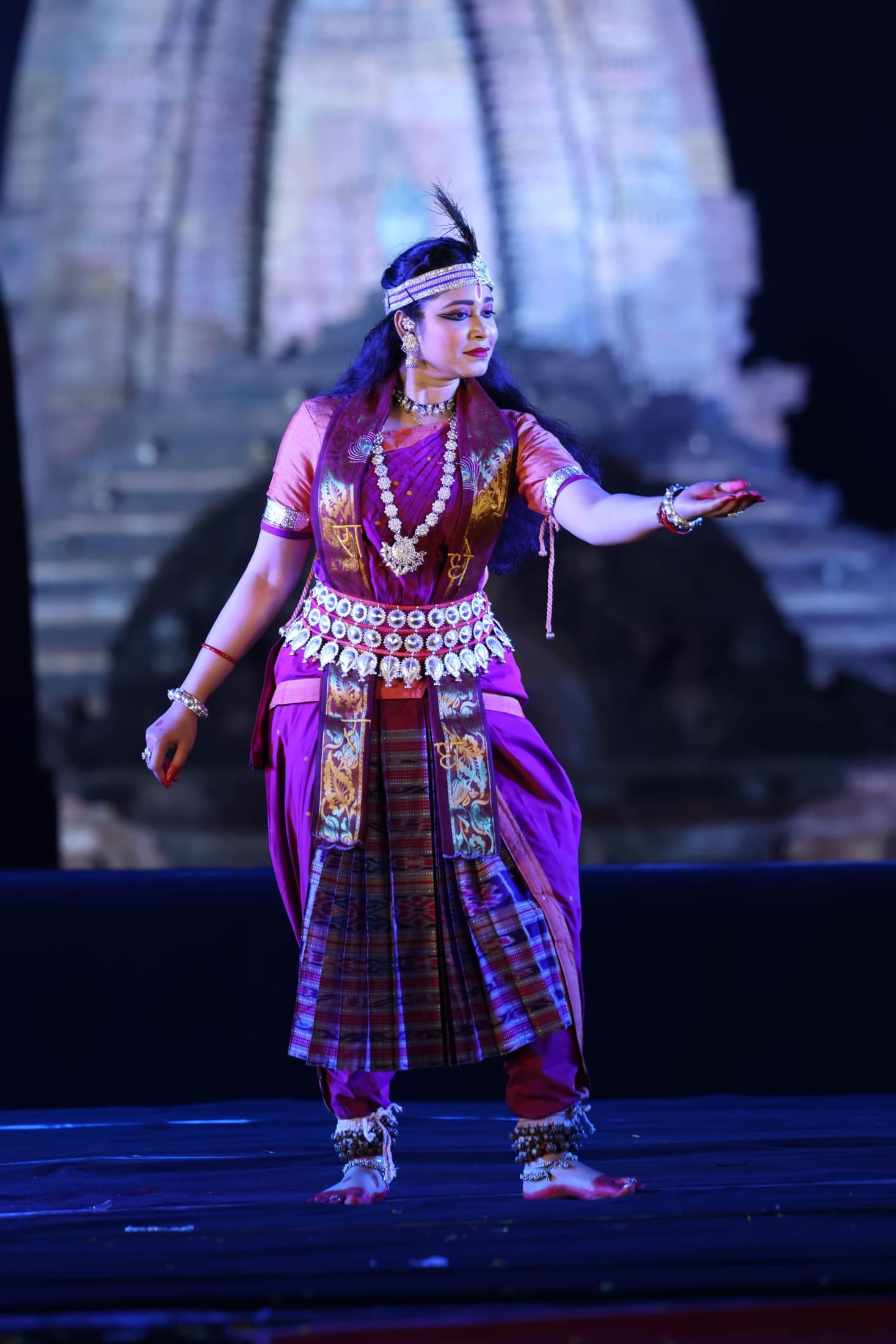 Sambalpuri folk dancer in purple and gold costume, festival stage