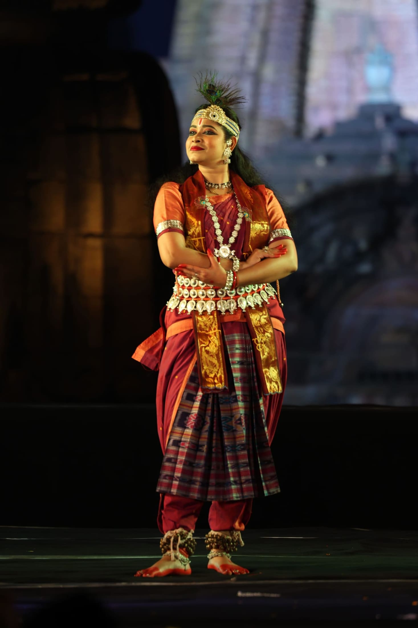 Odissi dancer in gold-trimmed costume with peacock feather headdress