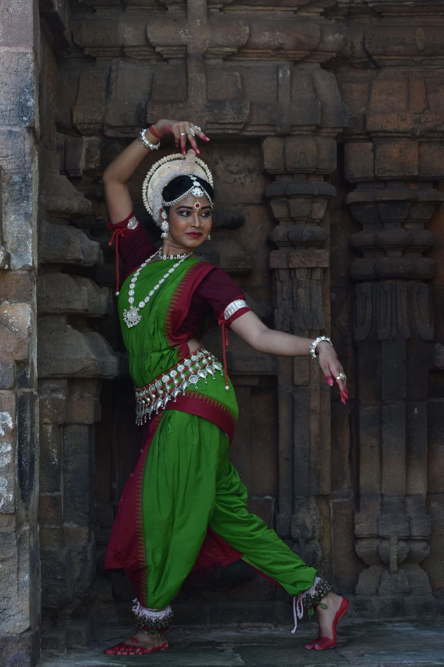 Odissi dancer in lunging pose against ancient temple wall