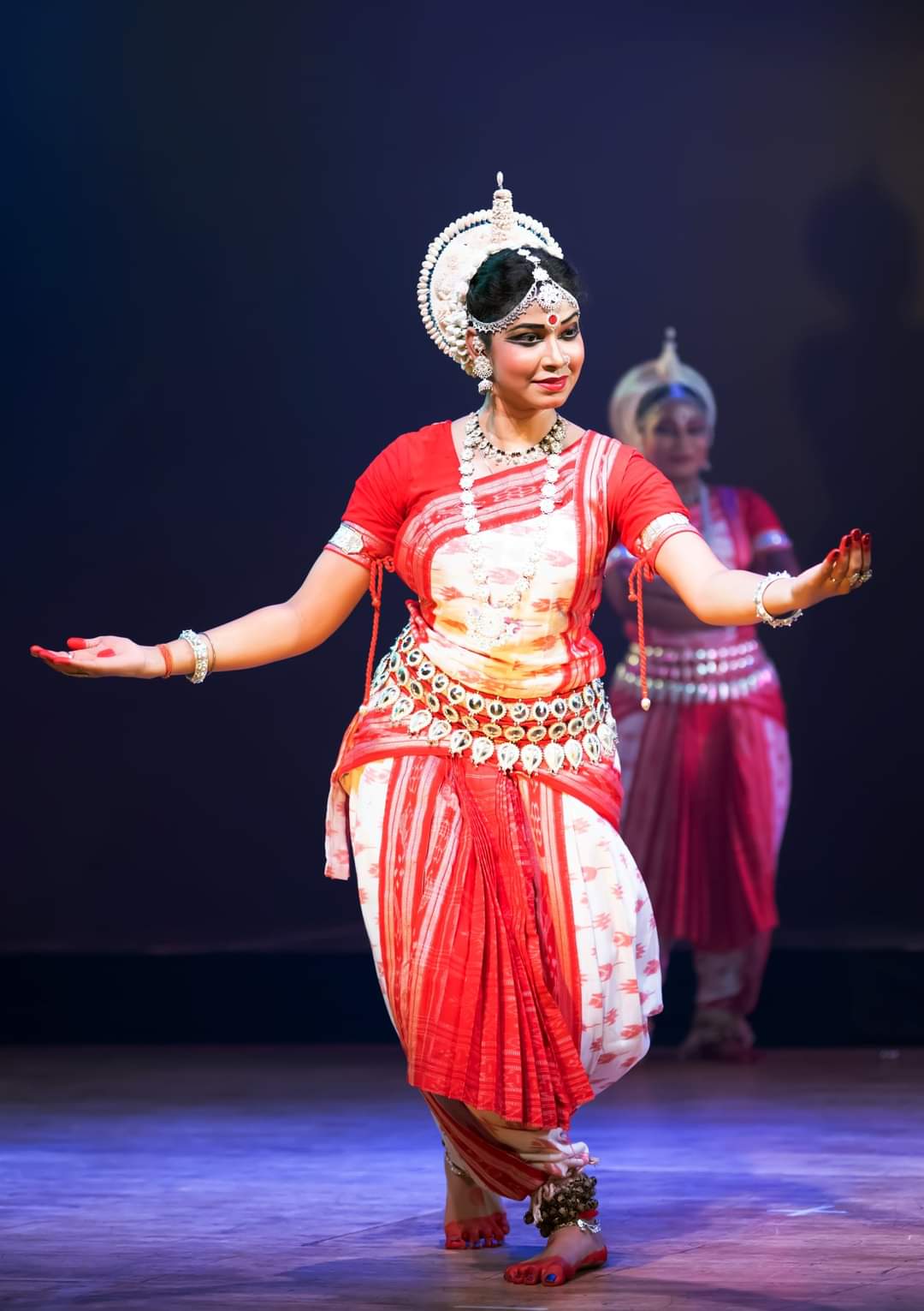Odissi solo performance in red and white costume on stage