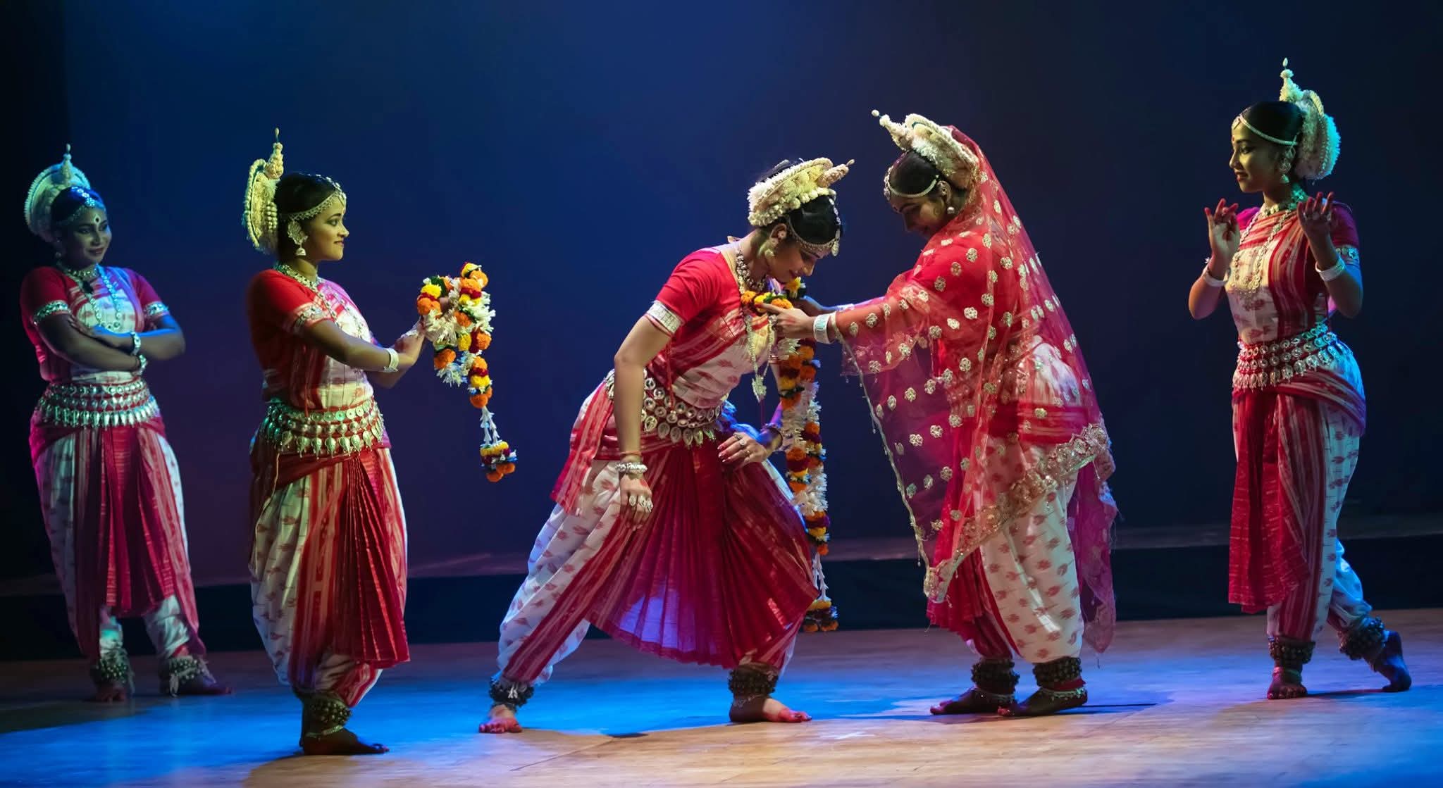 Guru blessing a student with a floral garland on stage