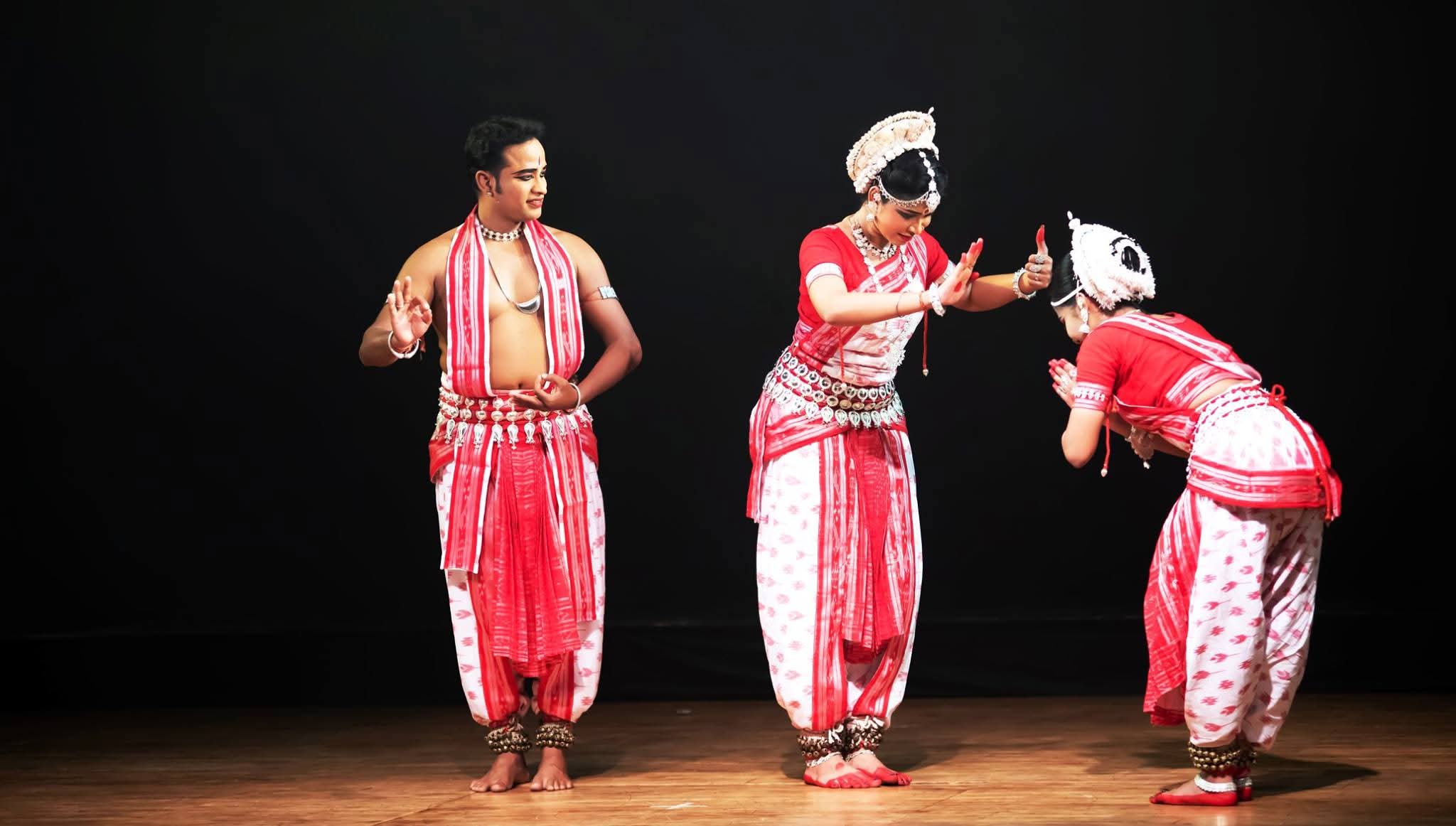Narrative Odissi performance with male and female dancers in red costumes