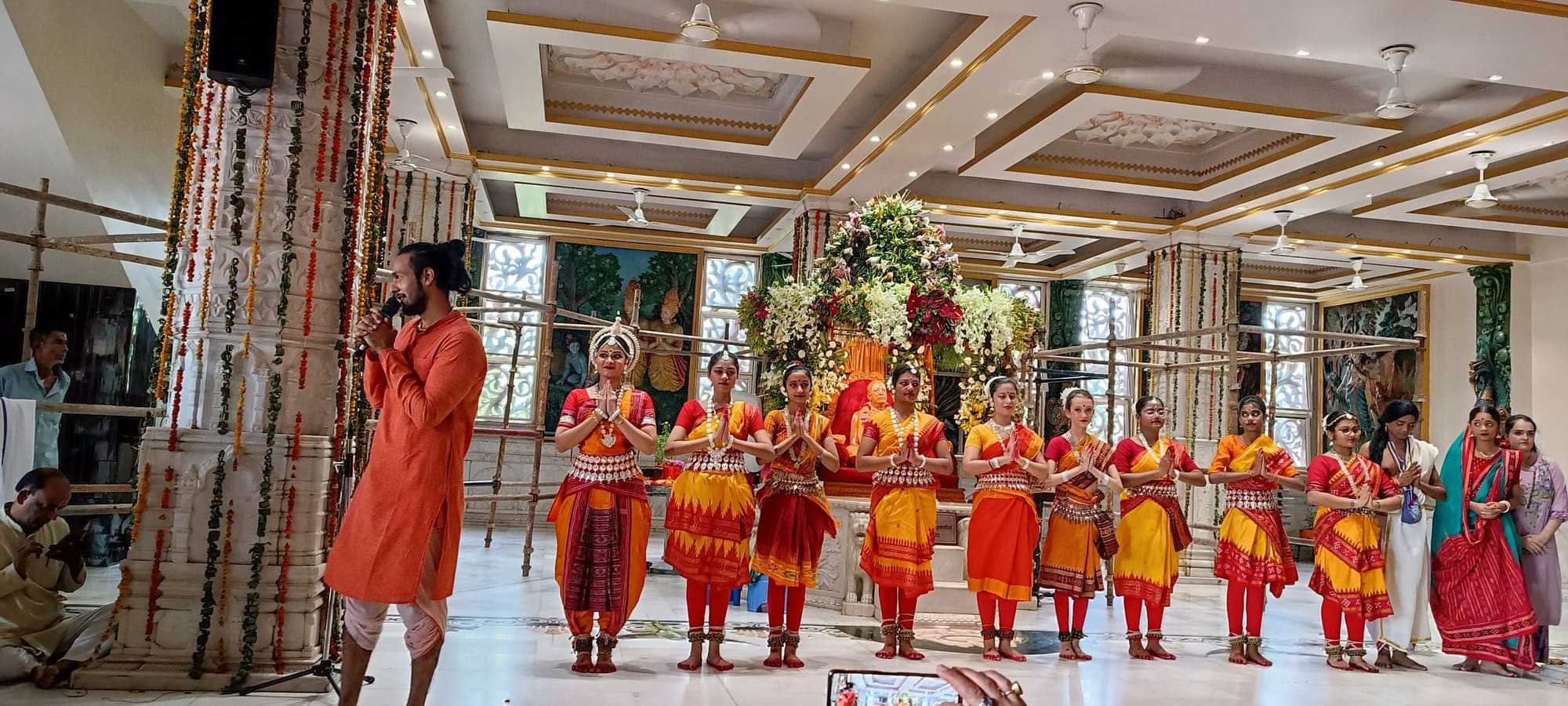 Group of dancers bowing in prayer before the guru murti at a temple hall