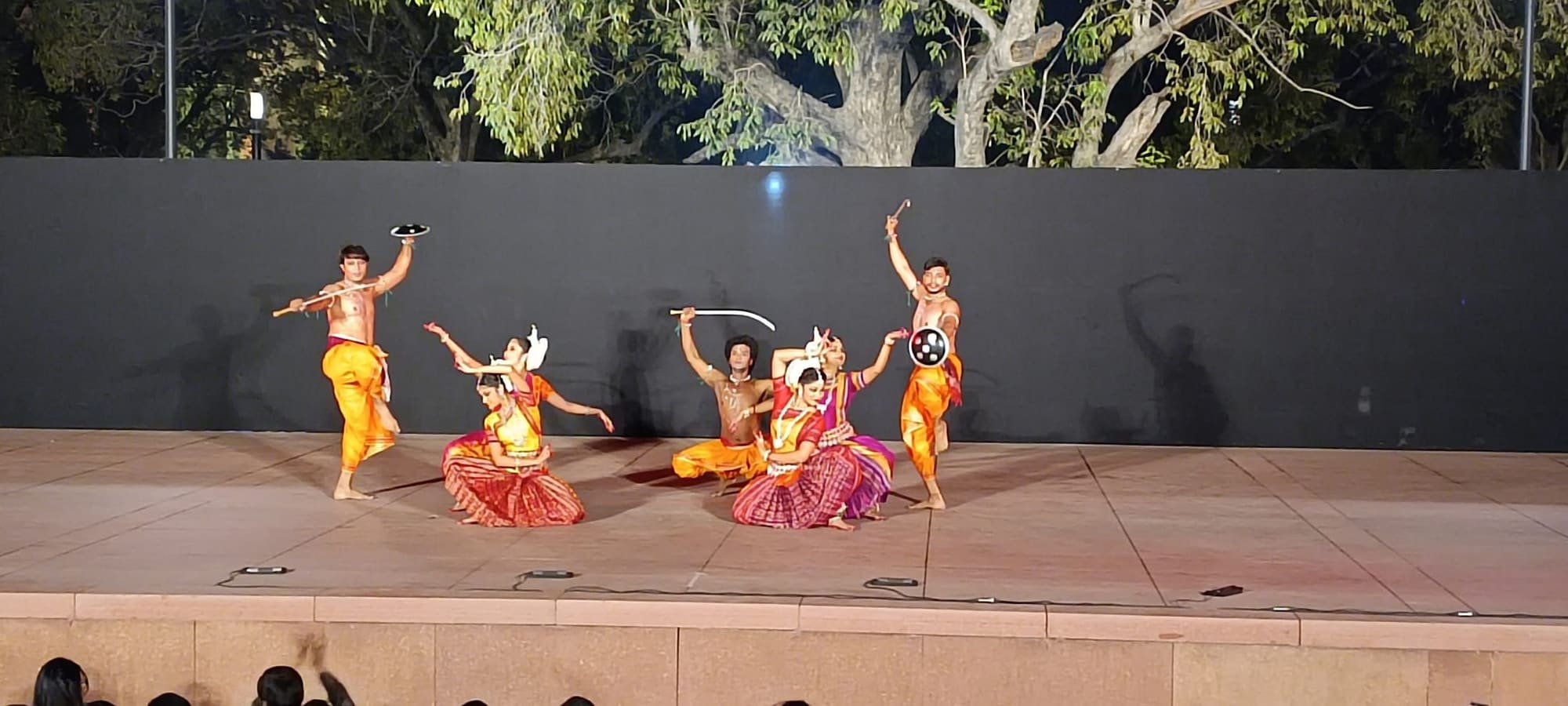 Outdoor evening performance depicting a mythological battle scene with swords and shields