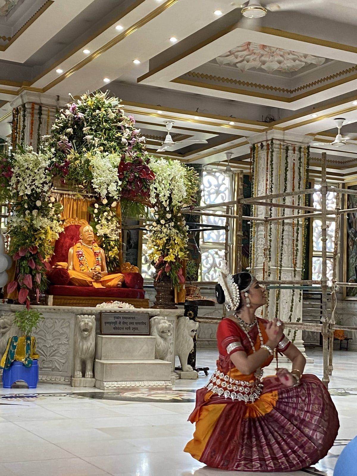 Odissi dancer in prayer pose before a temple shrine