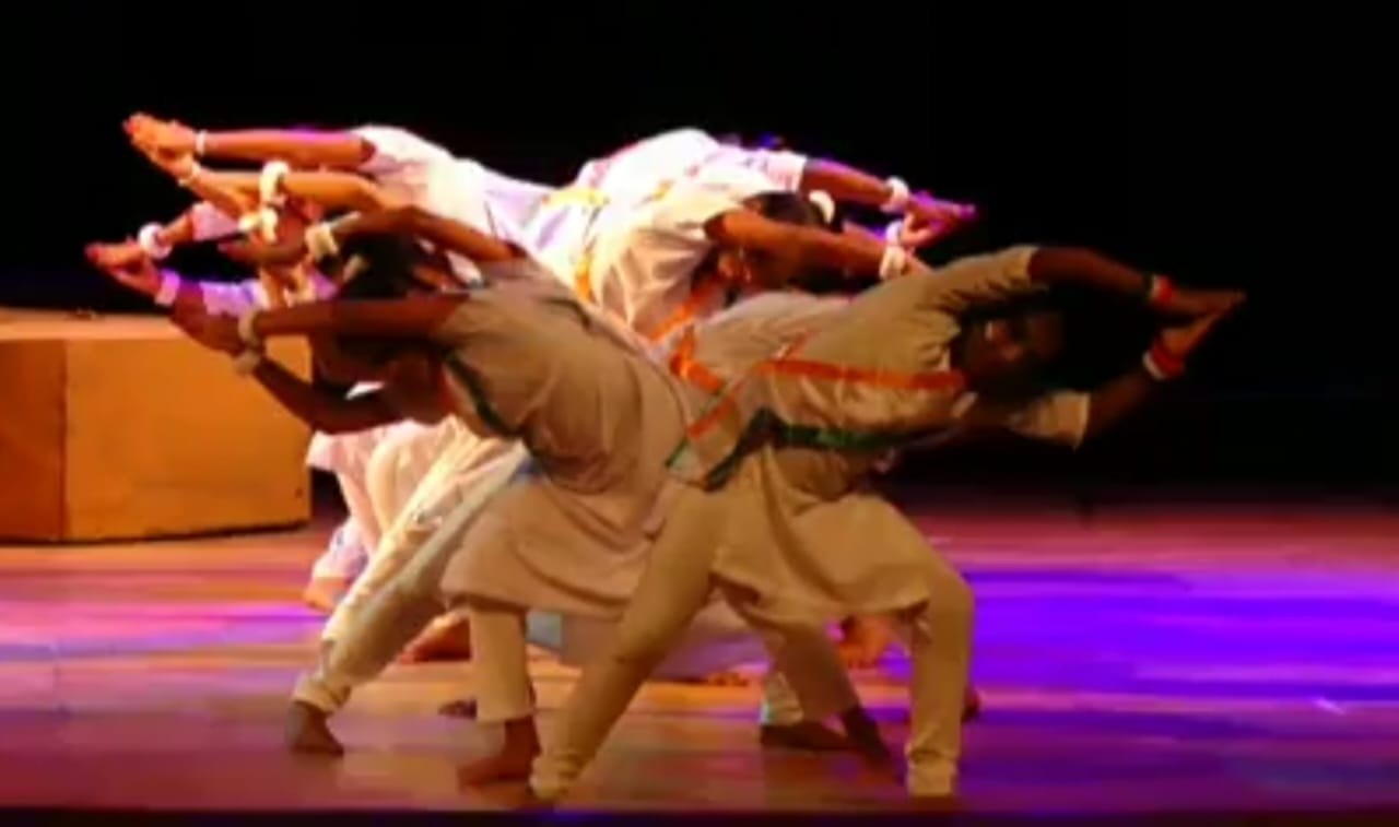 Students in white patriotic costume in a dynamic diagonal formation on stage