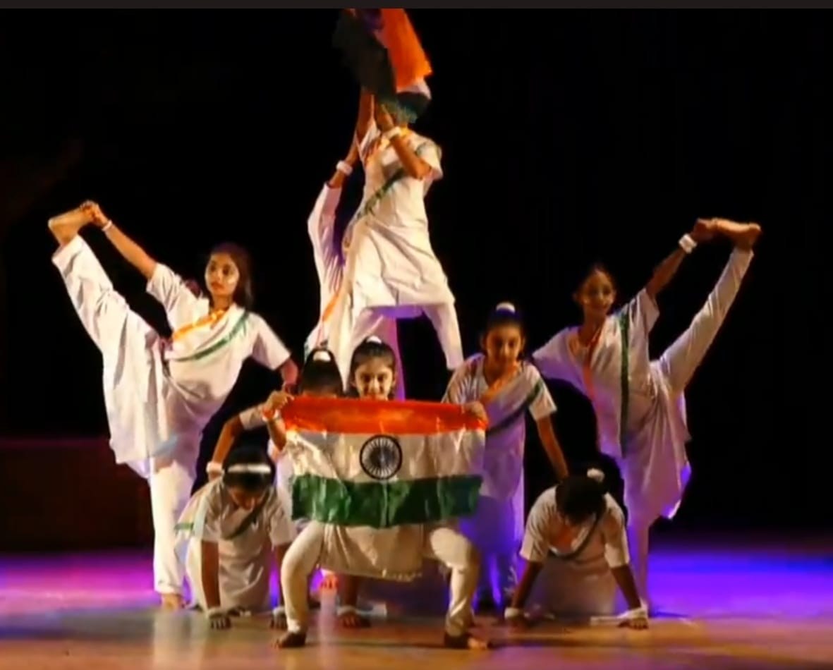 Students in white costume forming a pyramid around the Indian tricolor flag on stage